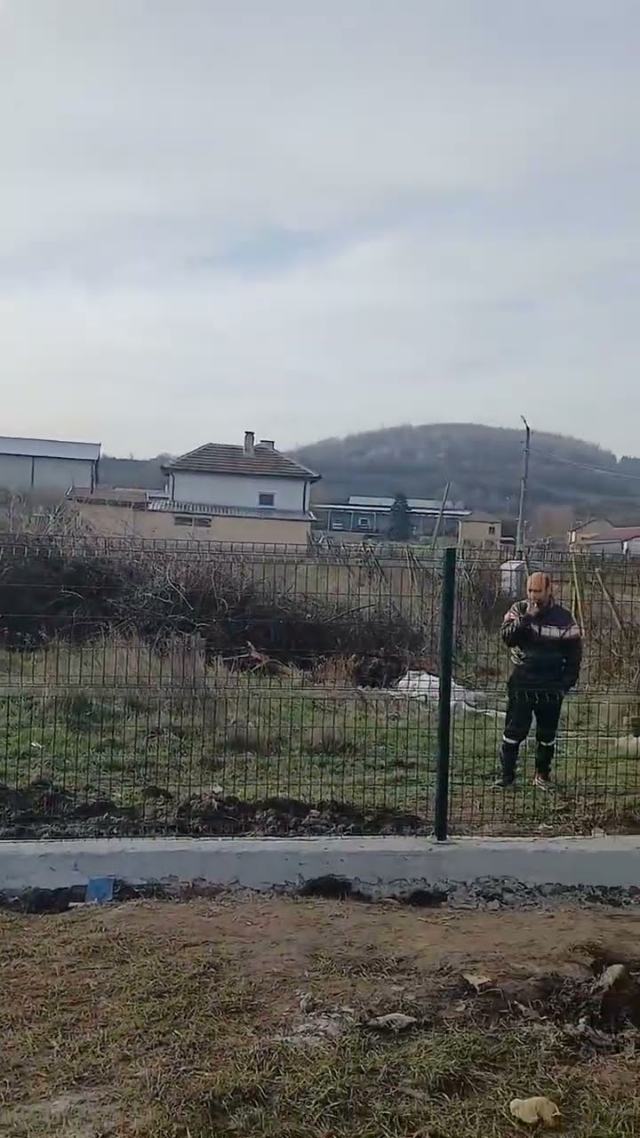 Вертикален кадър от видео с изграждане на ограда и почистване на двор.